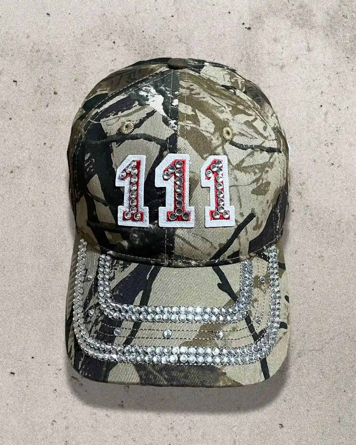 Camo print cap with sparkling rhinestones and bold 111 patch design.