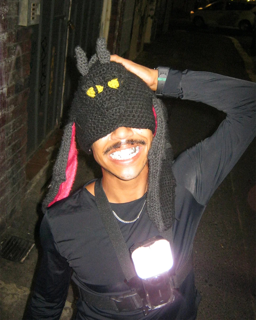 A man dons a unique hat featuring a face, showcasing Bullyboy's guerrilla marketing at Cape Town's First Thursday event