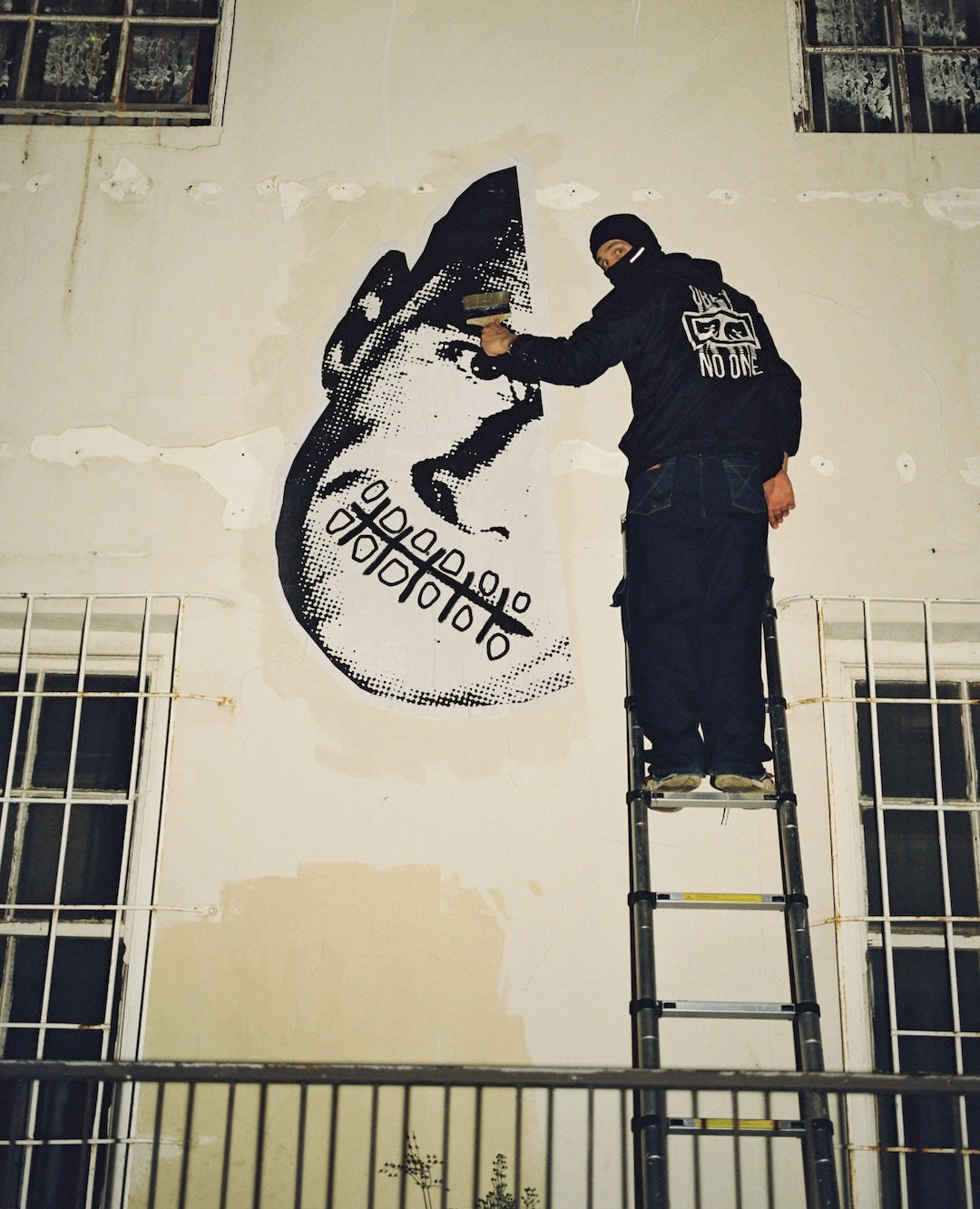 Person painting a large black and white mural on a wall.