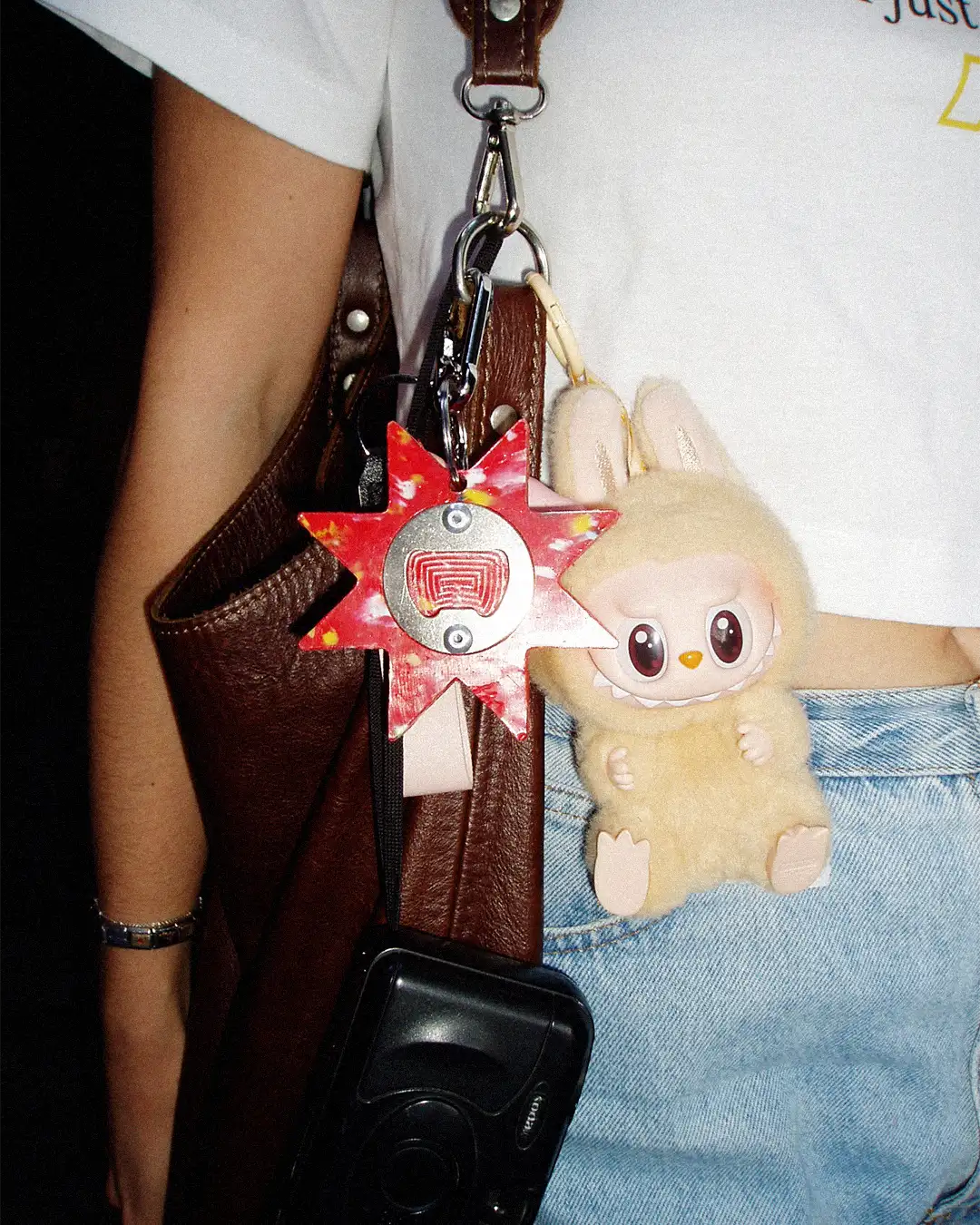 Girl with leather handbag and keychain accessories attached to it including a Labubu and the Bullyboy star utility keychain