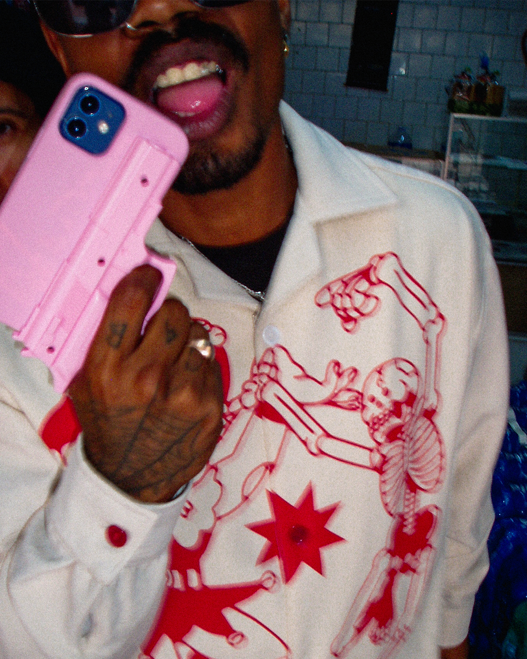 A stylish man opens his mouth with a fake toy pistol phone case while wearing the newest Bushy Wopp heavy duty button up shirts