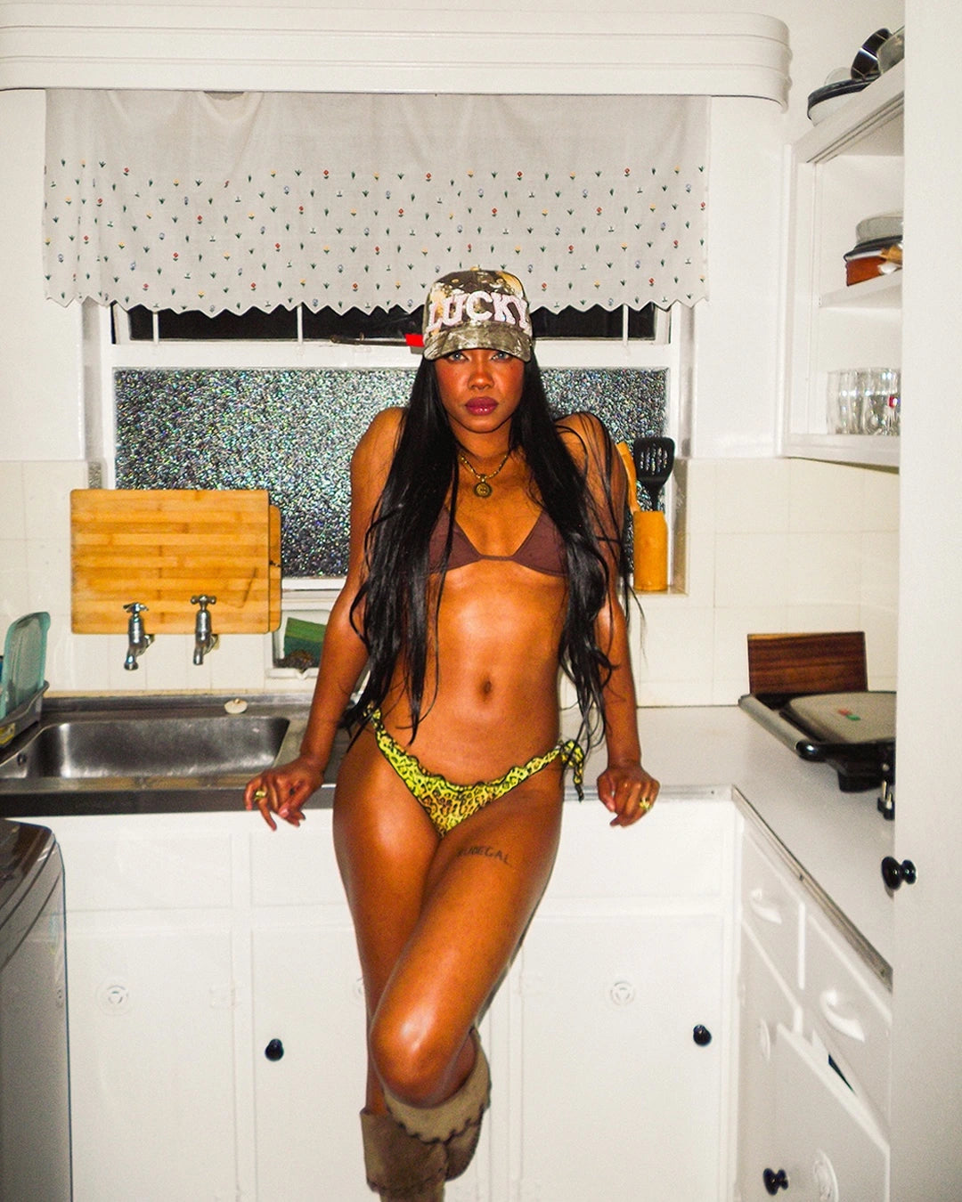 Person wearing a cap and green bikini in a kitchen