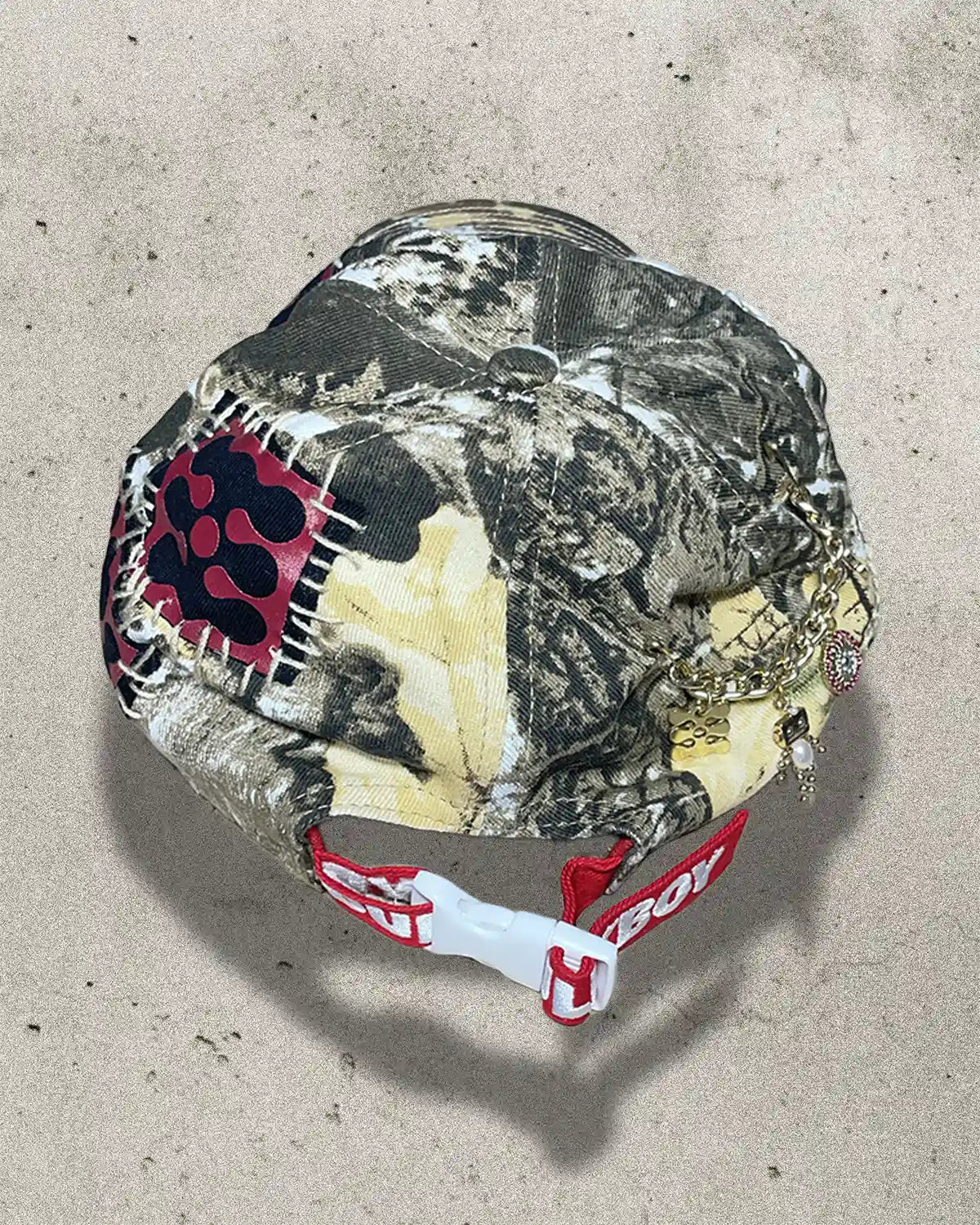 Camouflage-patterned helmet with a red and white logo on a concrete surface