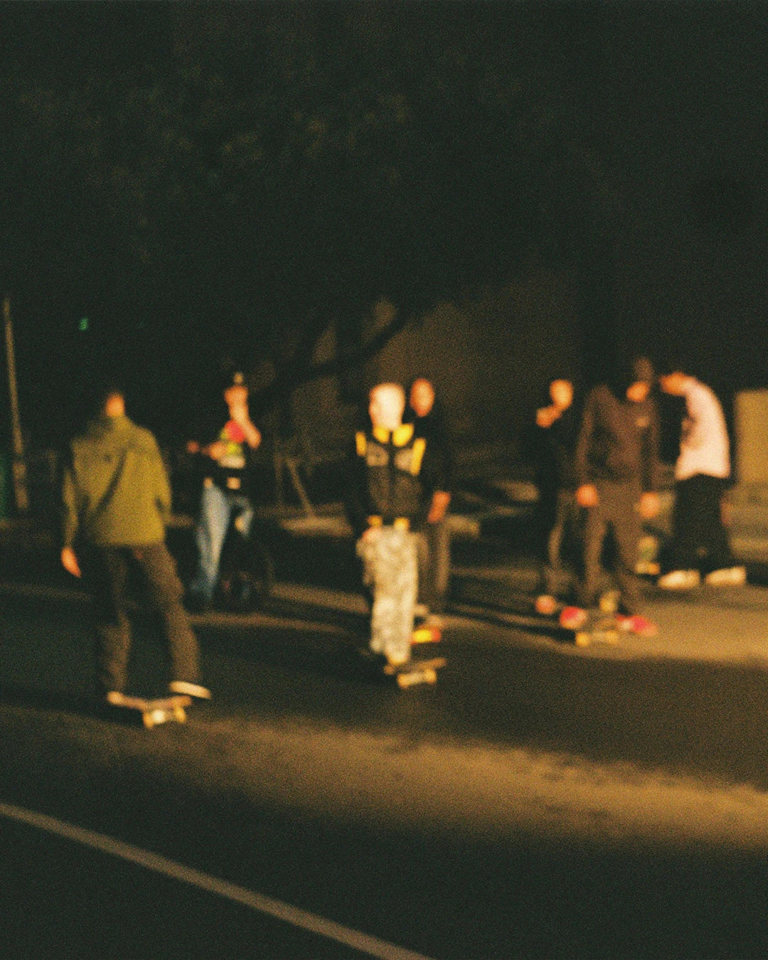 A group skateboards on a street at night, showcasing premium South African streetwear and a vibrant urban atmosphere