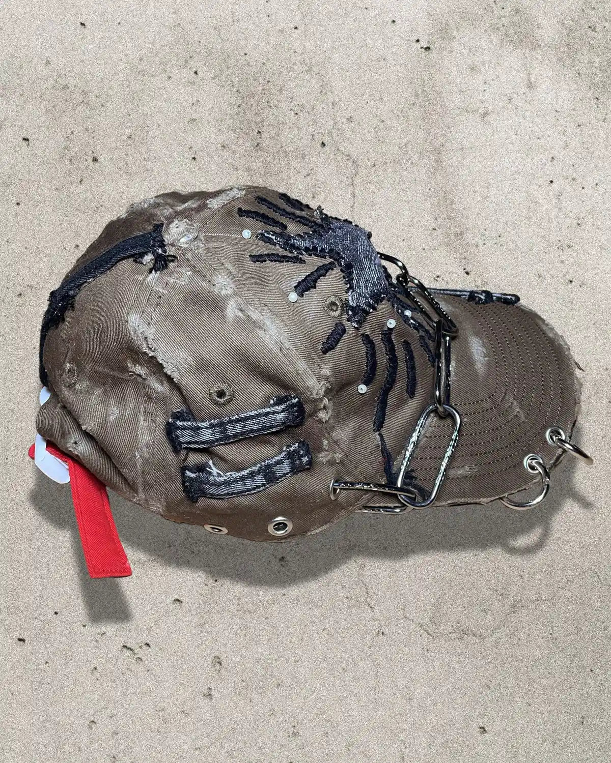 Brown baseball cap with black spider design on a beige surface