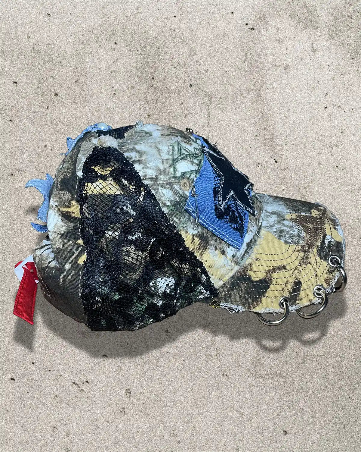 Camouflage-patterned cap with various patches on a beige surface