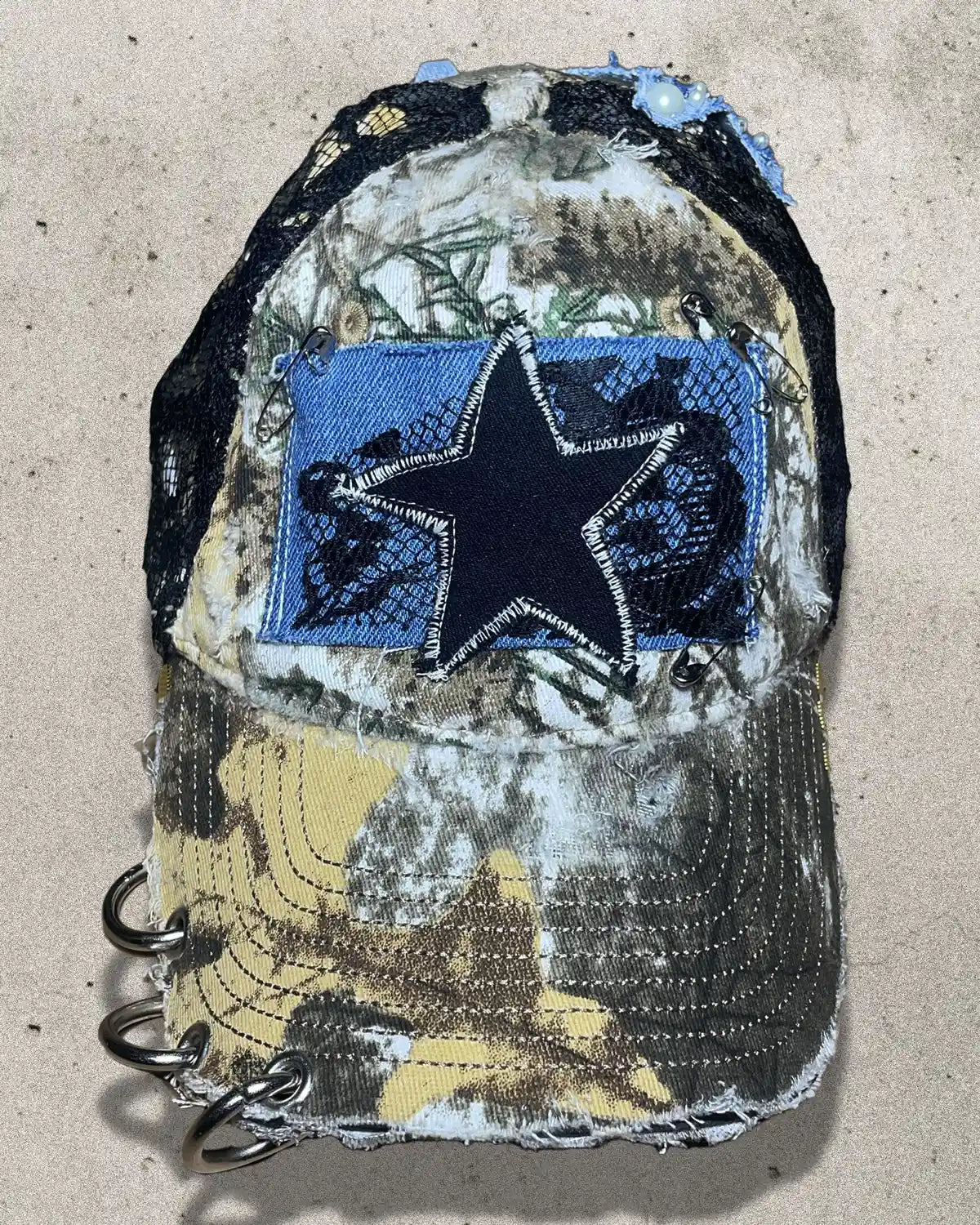 Camouflage-patterned cap with a blue star patch on a beige background