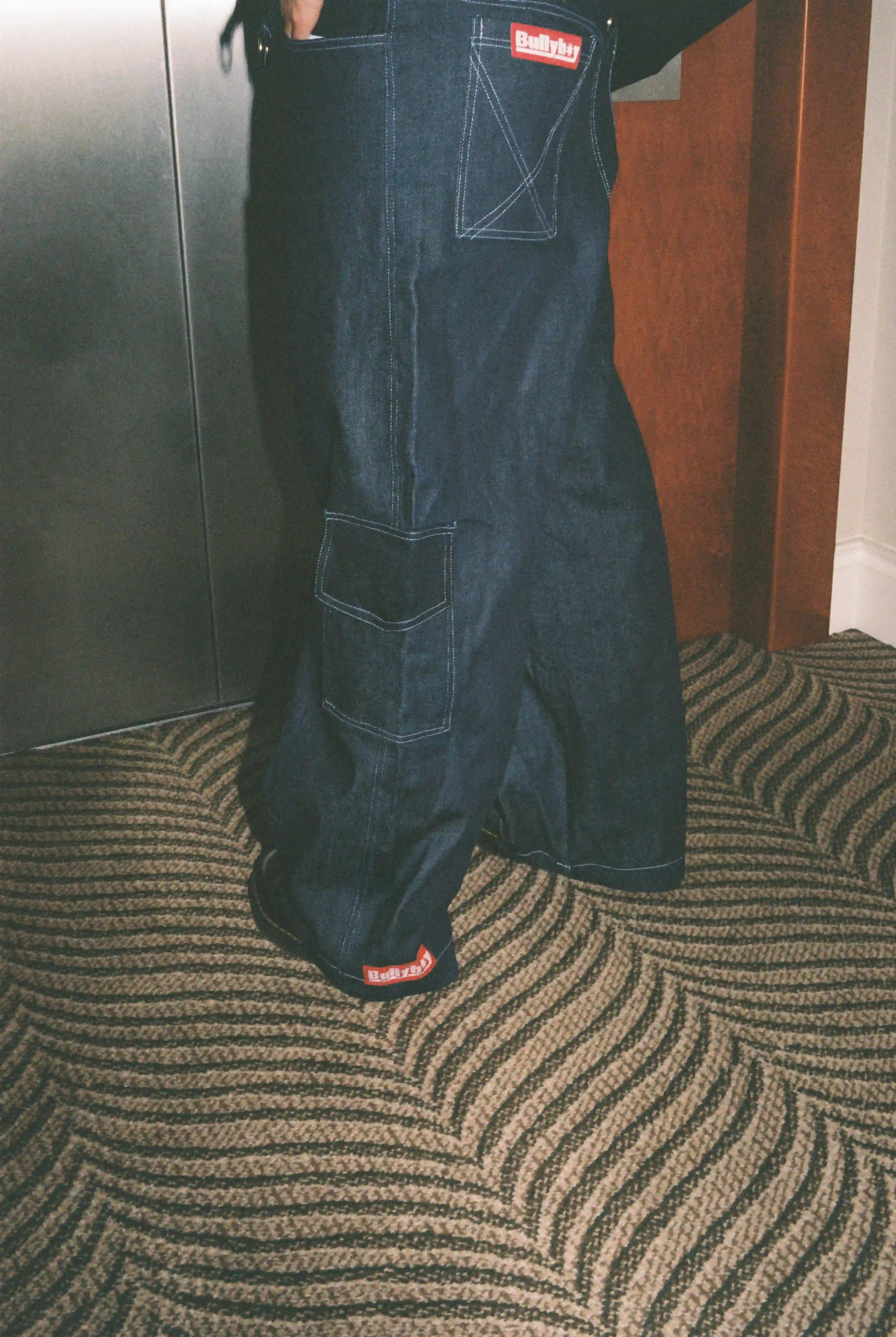 A fashionable man stands on a luxurious carpet, embodying Bullyboy streetwear in Cape Town.