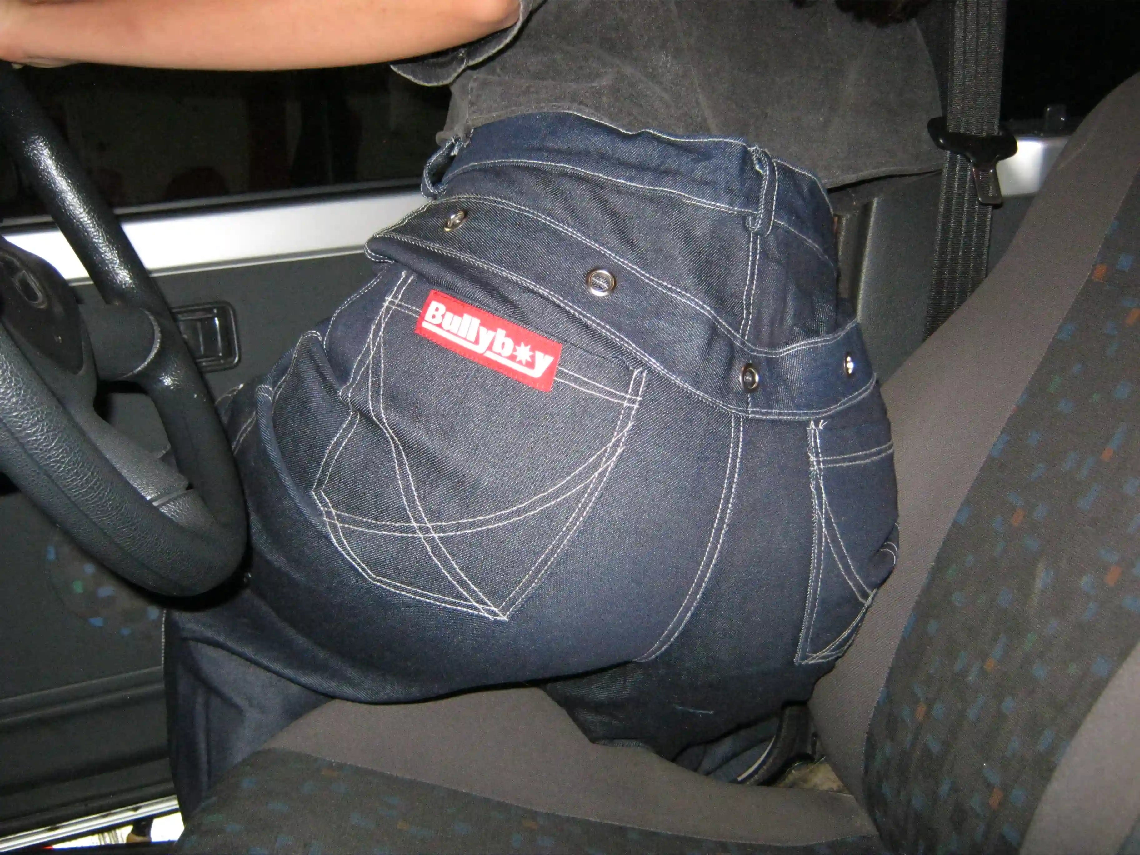 A woman in a car, showcasing her stylish baggy denim trousers from Bullyboy, epitomizing South African streetwear elegance.