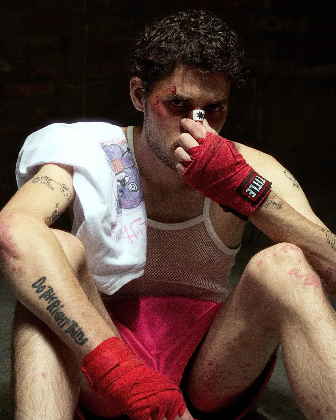 A contemplative man in Bullyboy streetwear sits on a mat, hands on his face, embodying the spirit of boxing in Cape Town.