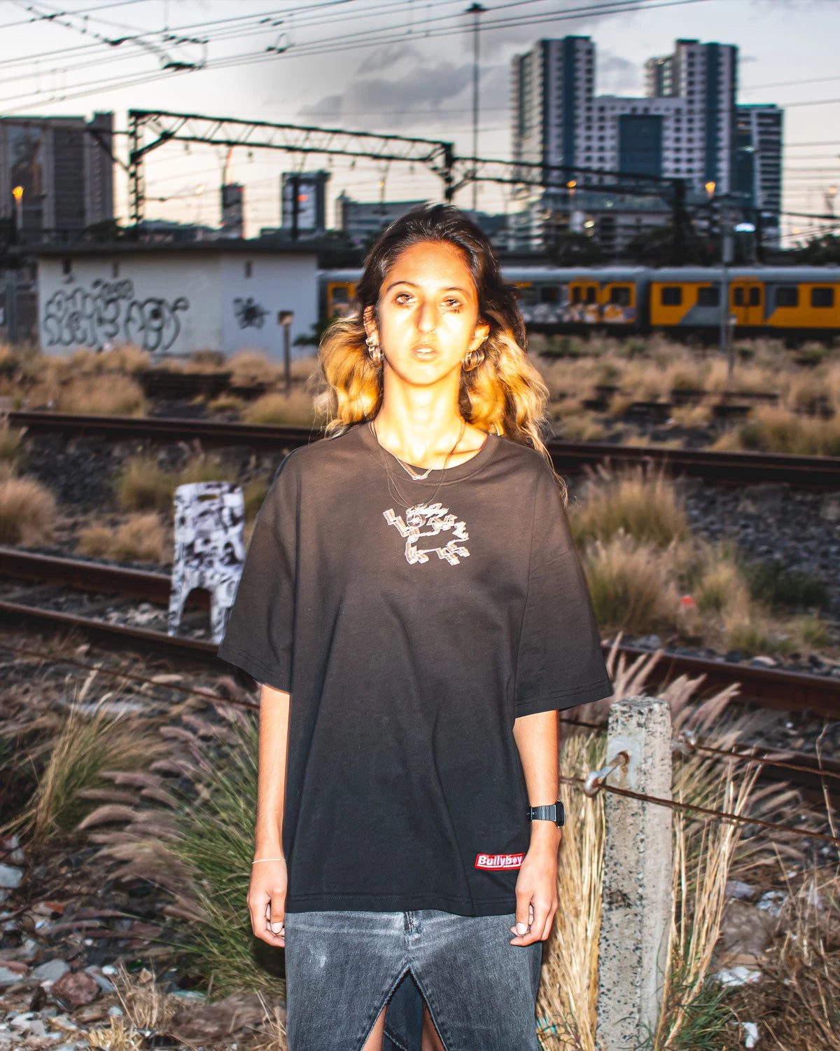 A model wearing a black oversized T-shirt with a graphic design on the chest and a 