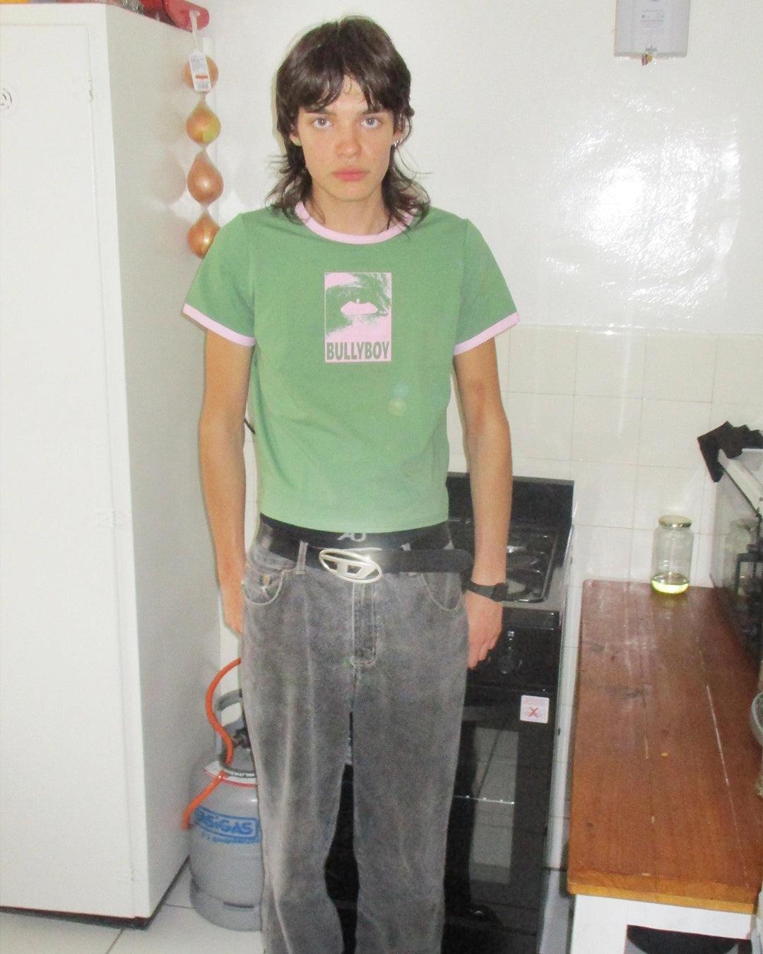 Person wearing a green 'Bullyboy' t-shirt in a kitchen setting
