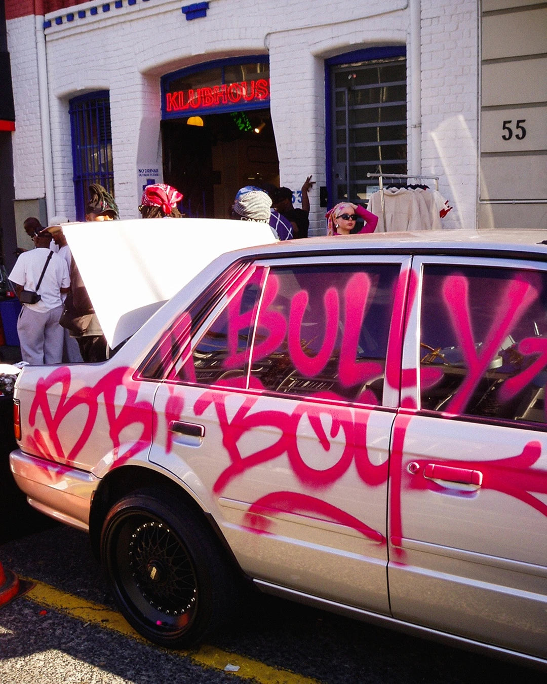Car with pink graffiti on a street scene