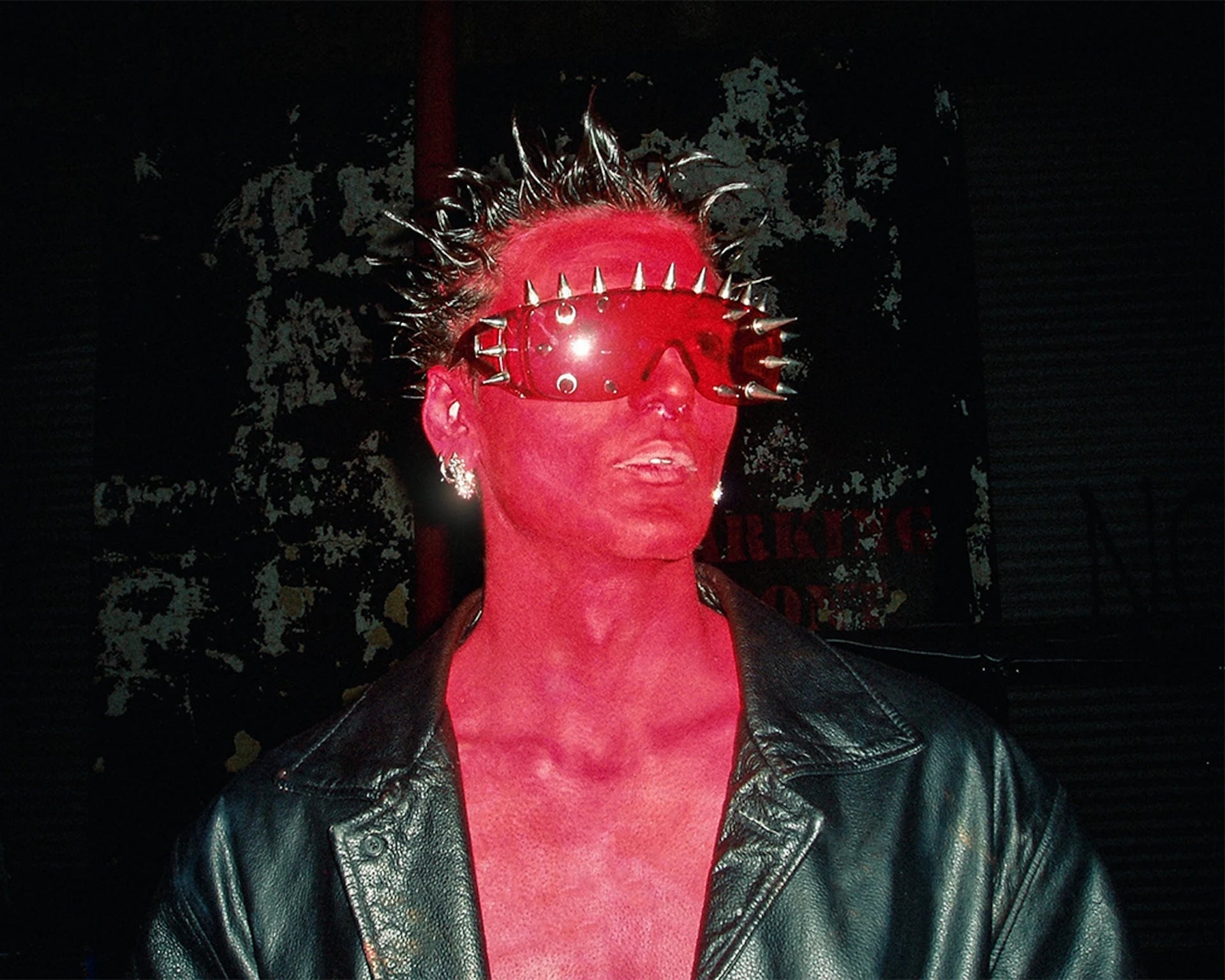 Person wearing a red outfit and spiky headpiece with dark background