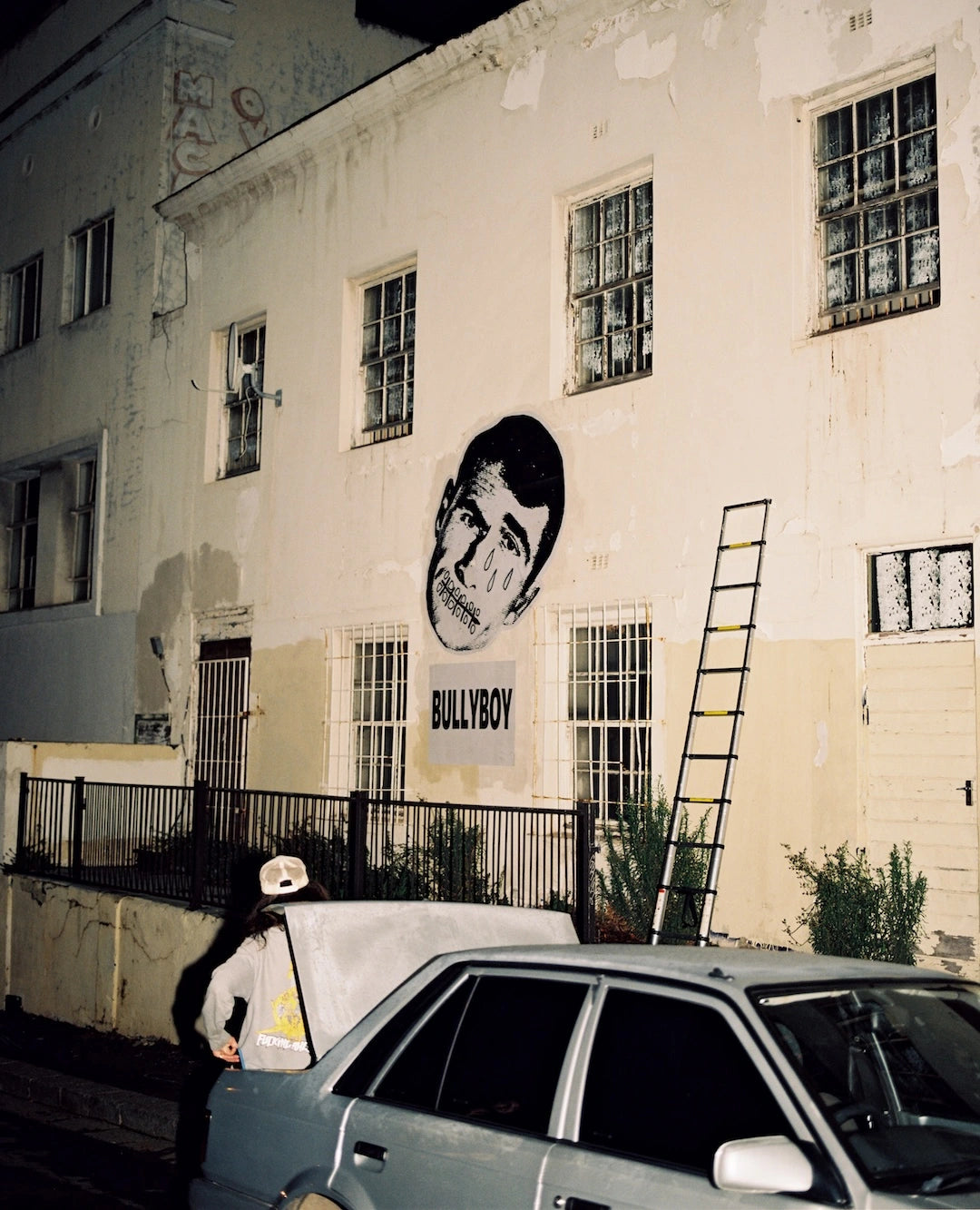 Building with a mural of a face and the word 'BULLYBOY' on a white wall.