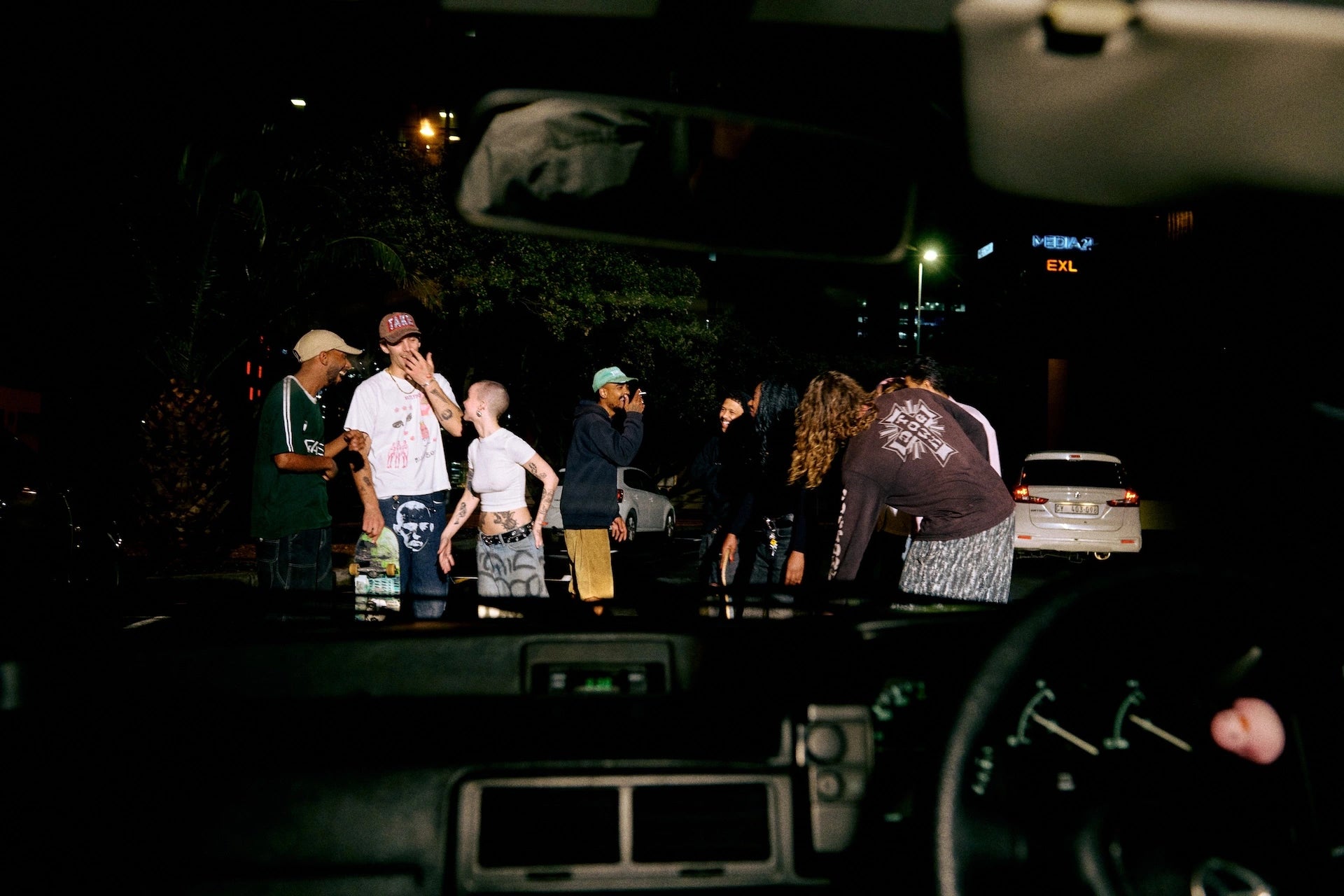 Group of people standing outside a car at night