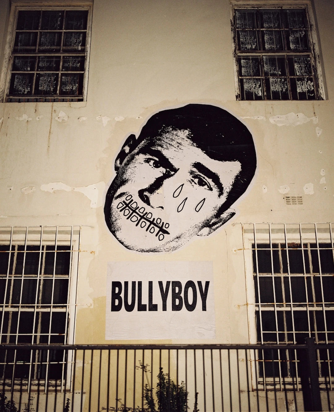 Stylized black and white mural of a face on a beige wall with 'BULLYBOY' text below.