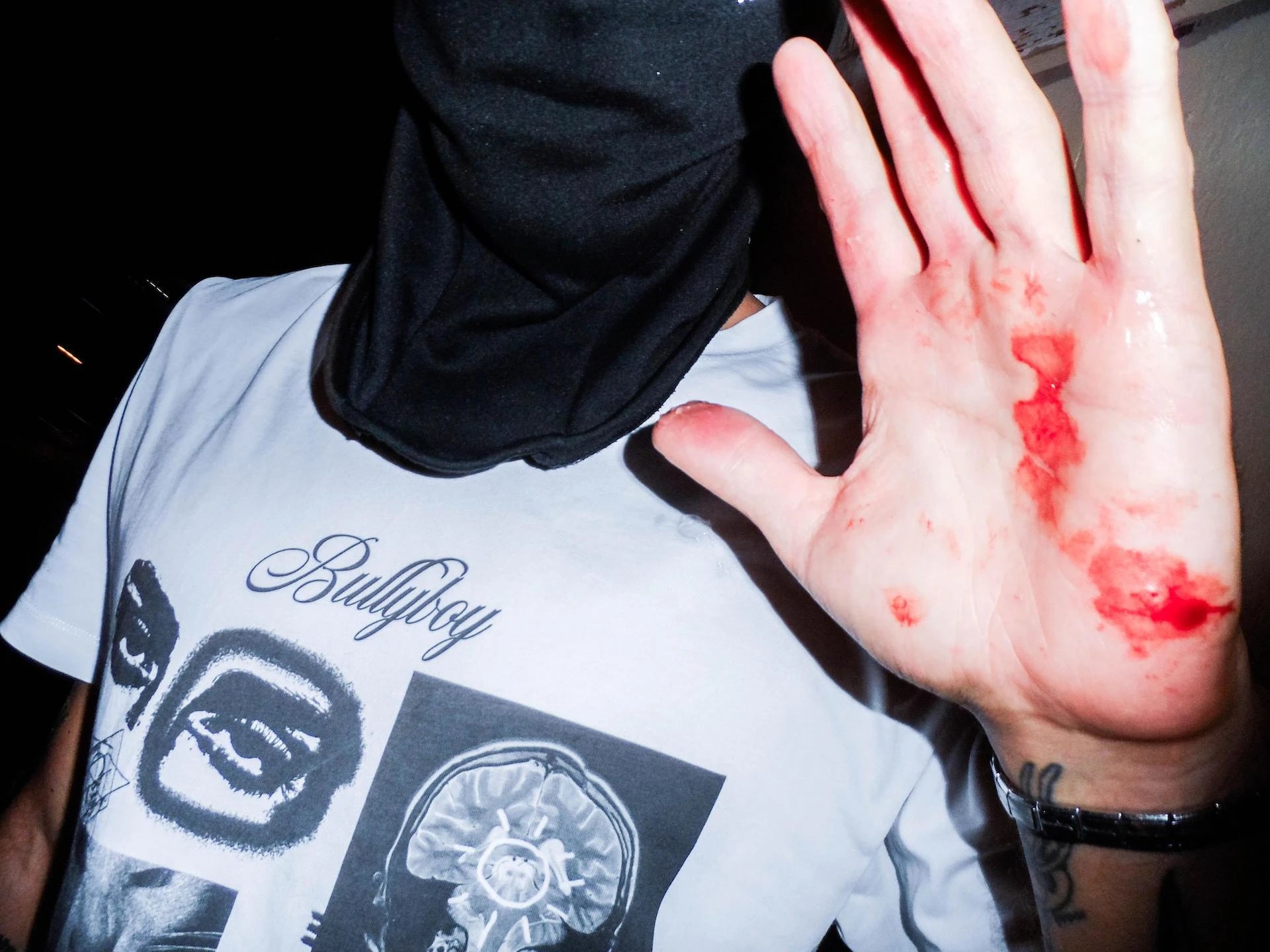 Person wearing a 'Bullyboy' t-shirt with a hand showing red substance on the palm.