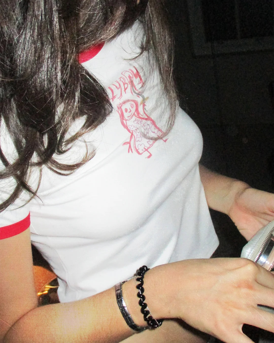 Female model digs through her makeup purse in a candid bathroom photoshoot while wearing the new Bullyboy red ringer tee