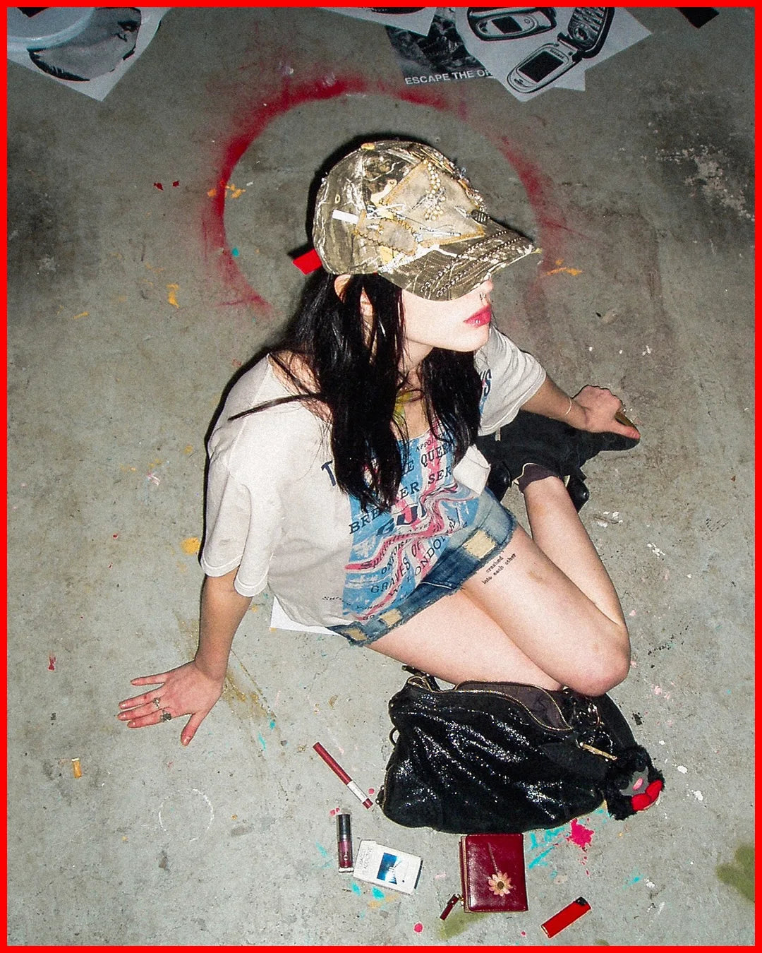 Person sitting on the ground with a backpack, surrounded by scattered items on a concrete surface.