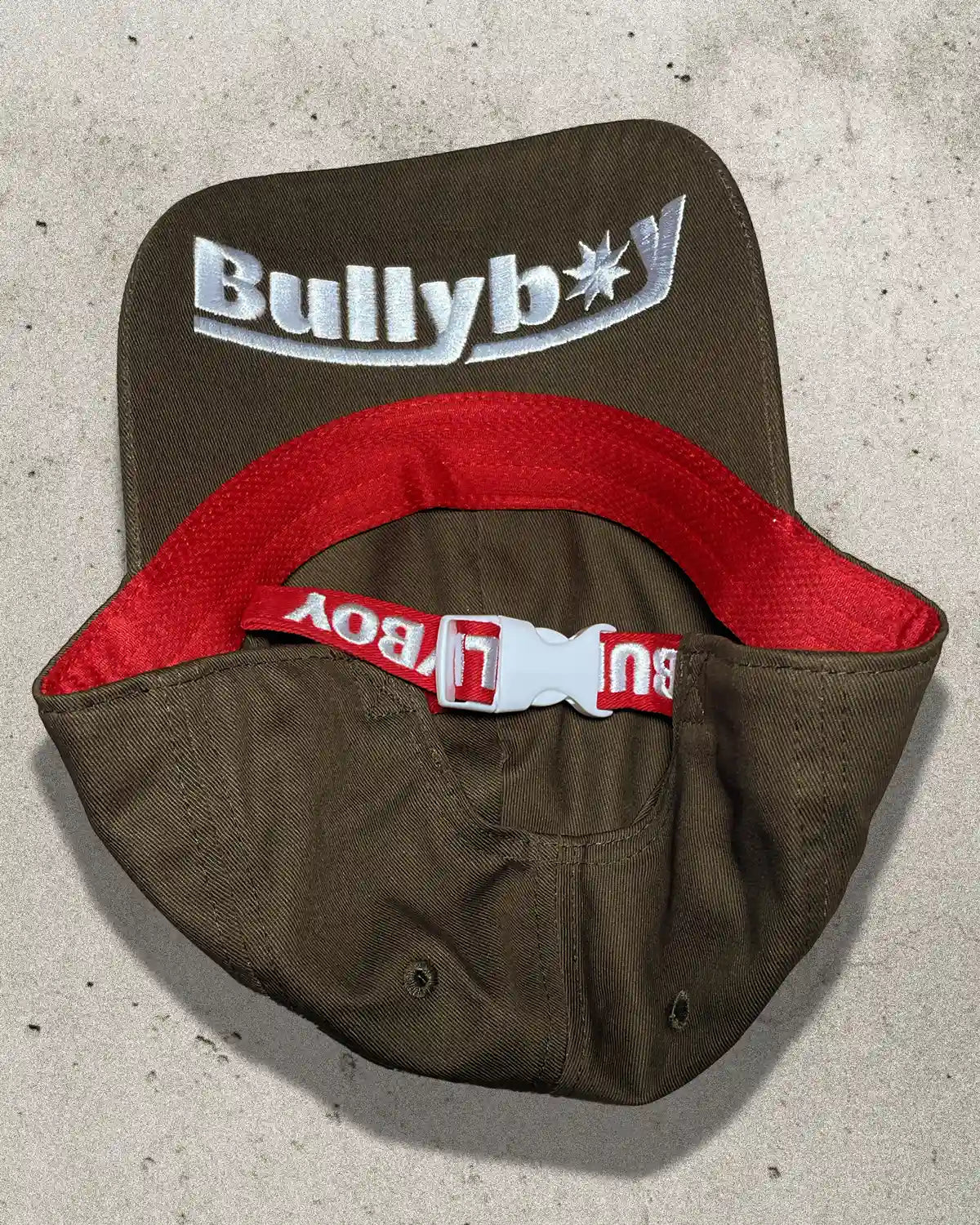 Macro shot of brown Bullyboy cap showing logo embroidery under brim and cotton fabric grain