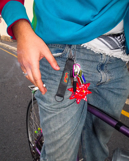 Male posing on a purple retro bicycle wearing trendy streetwear with the Bullyboy Star utility Keychain attached with a carabiner to his belt loop