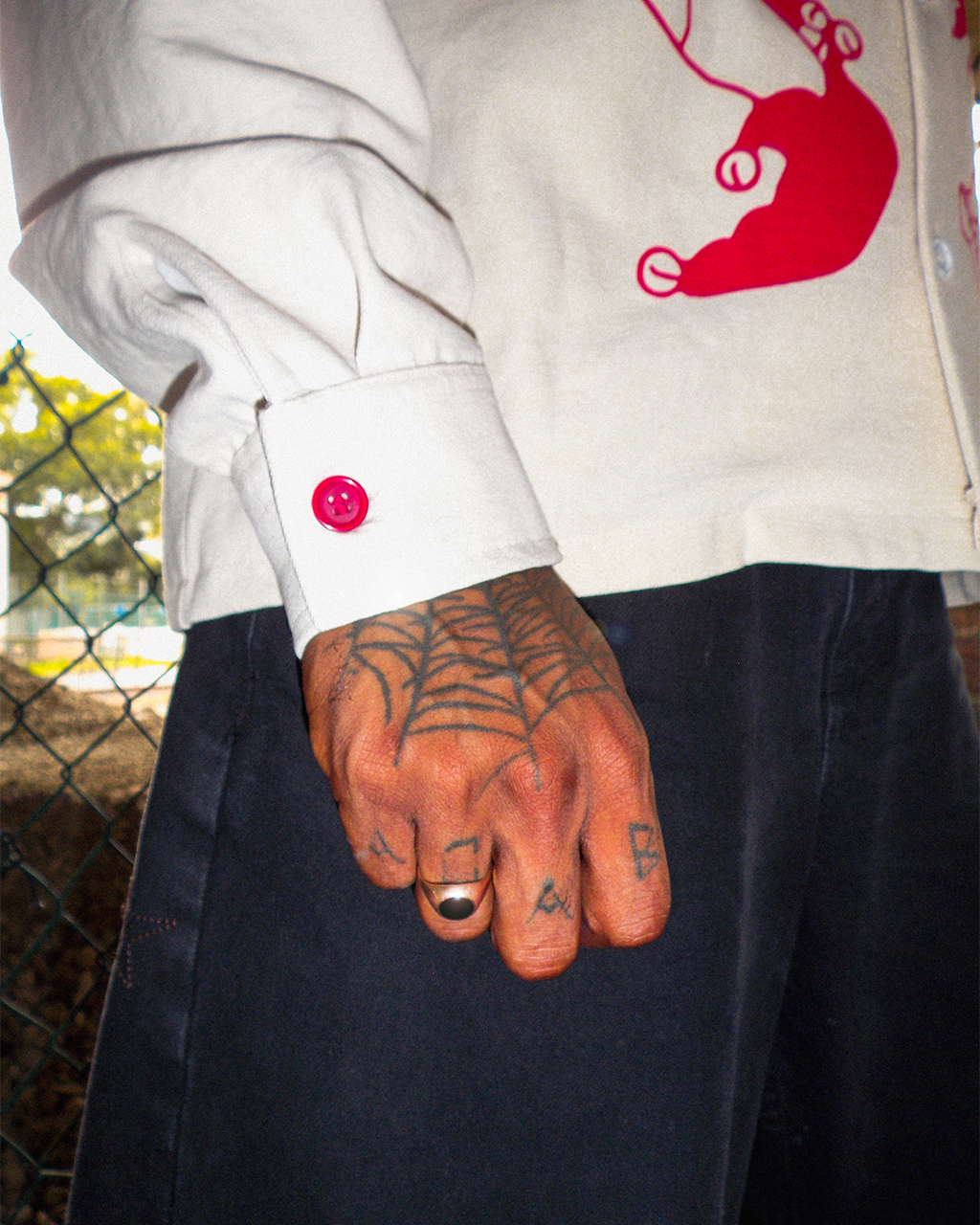 A detailed photo of the Bushy Wopp long sleeve cuffs while the model holds a fist with his hand full of tattoos