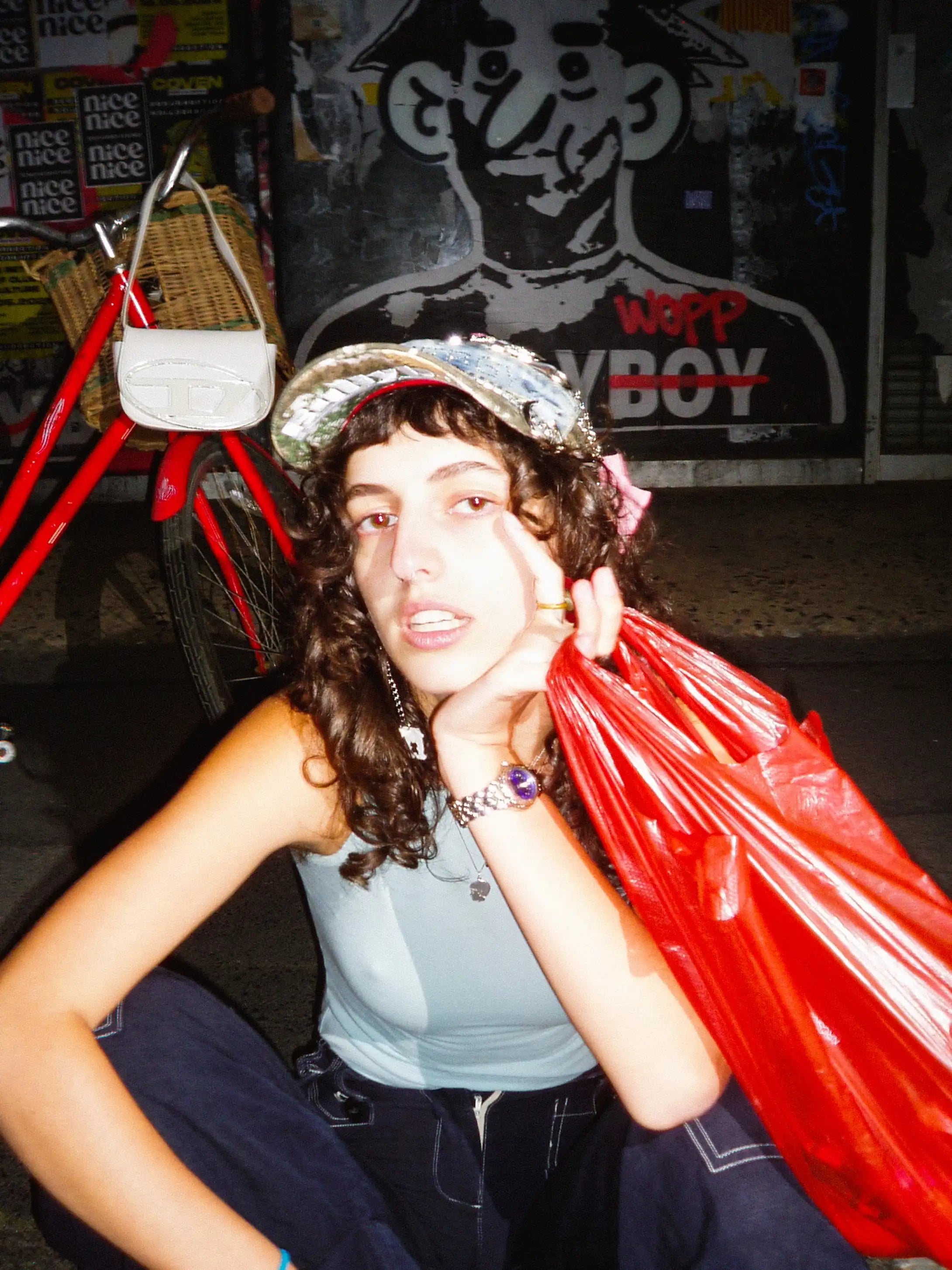 Person holding a red bag with a store and bicycle in the background
