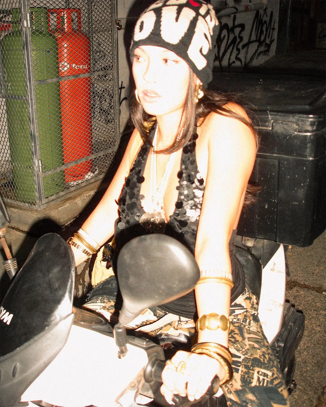 Person sitting on a motorcycle with a helmet and gloves, surrounded by industrial equipment.