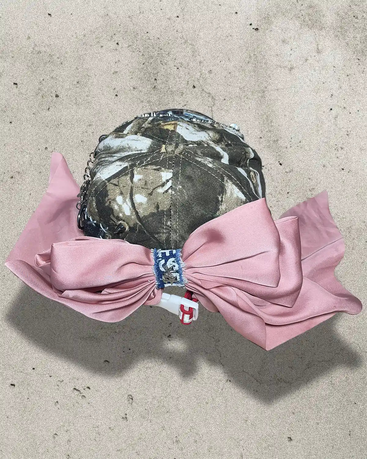 Camouflage swim cap with pink bow on a concrete surface