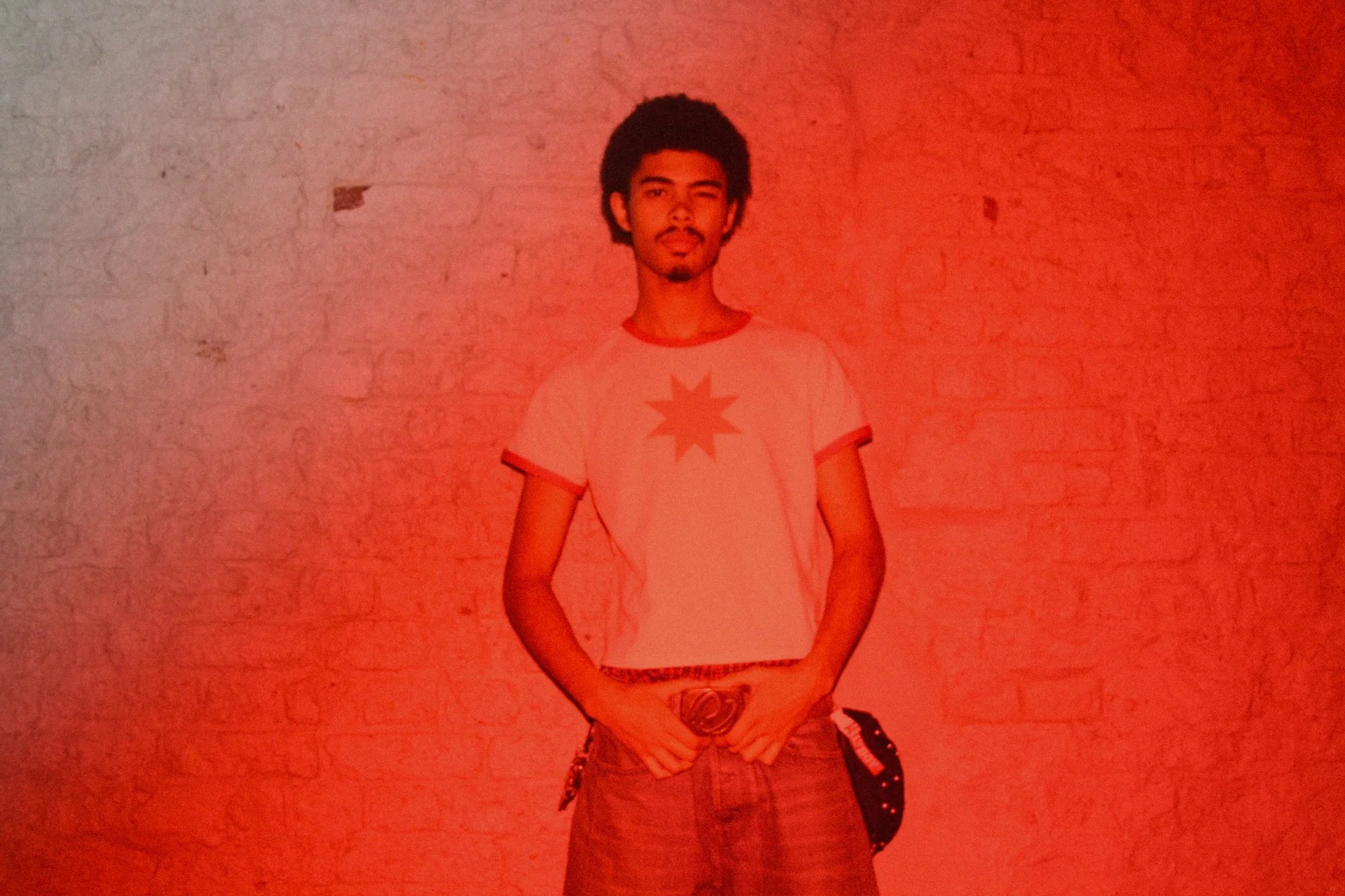 Person wearing a white t-shirt with a red star design against a textured red and gray background