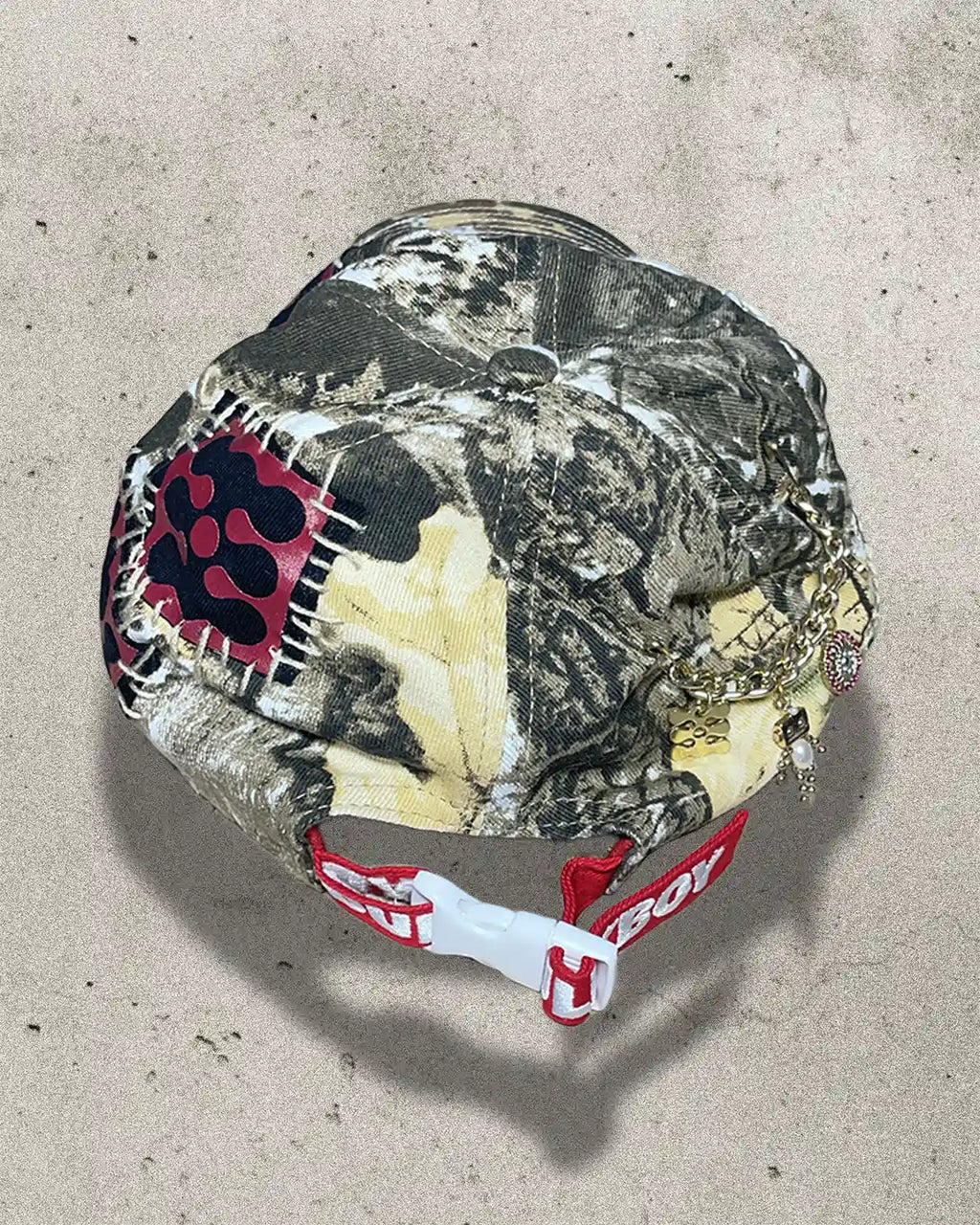 Camouflage-patterned helmet with a red and white logo on a concrete surface