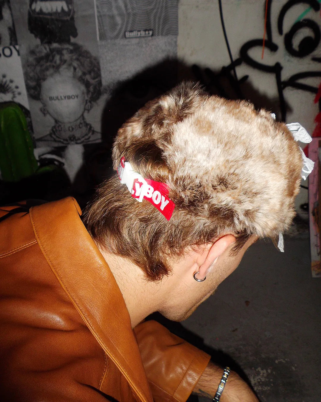 Man kneeling down with the back of his head wearing a Bullyboy one of one cap with the conic red strap