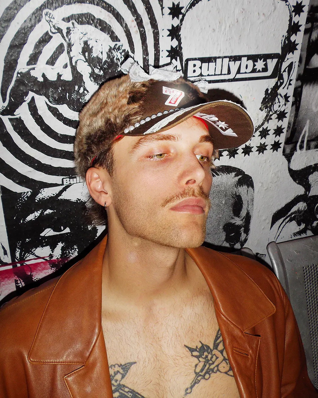 Man resting on a metal bench while wearing the new Bullyboy one of one fur cap during their editorial shoot