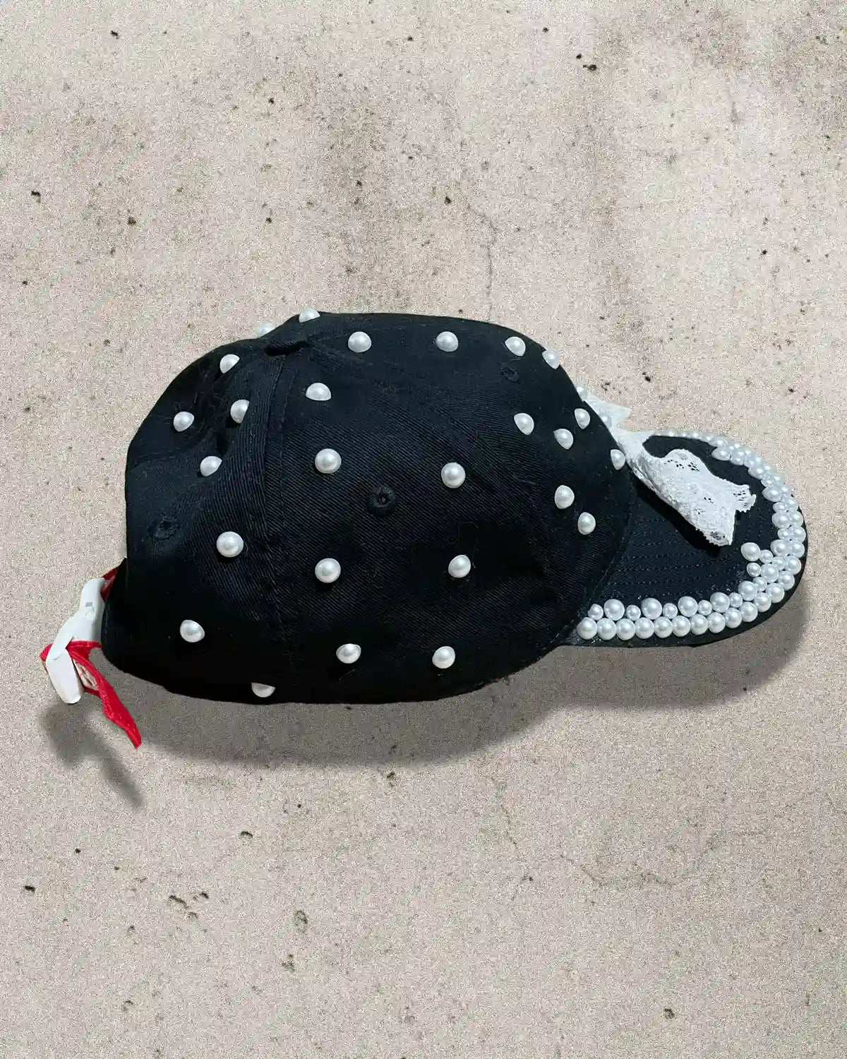 Chic and bold black cap with white bow and ornate pearl accents.