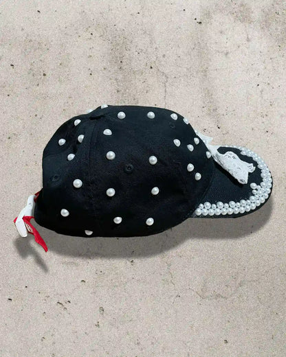 Chic and bold black cap with white bow and ornate pearl accents.