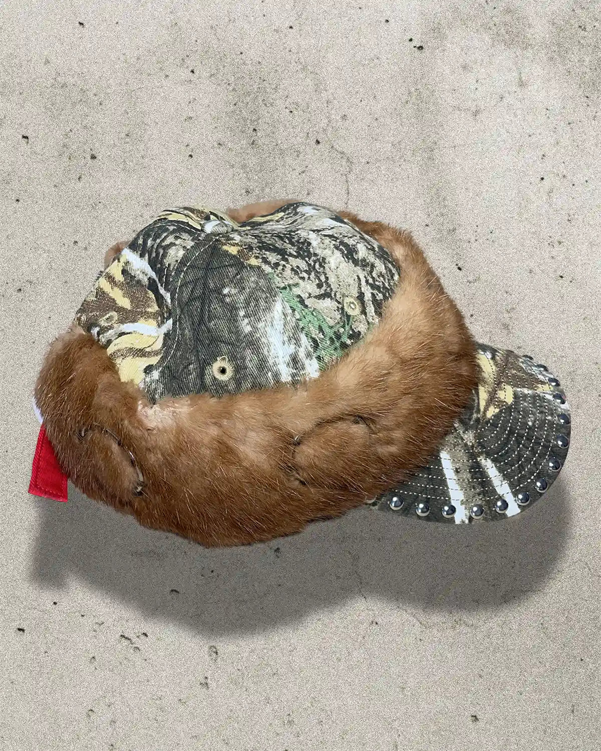 Plush toy resembling a beaver with camouflage and sequin details on a concrete surface