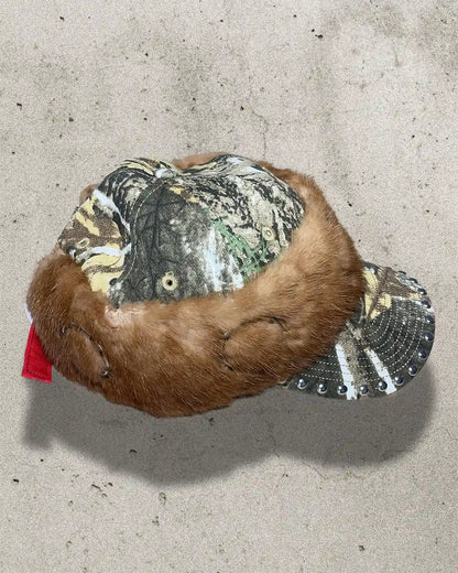 Plush toy resembling a beaver with camouflage and sequin details on a concrete surface