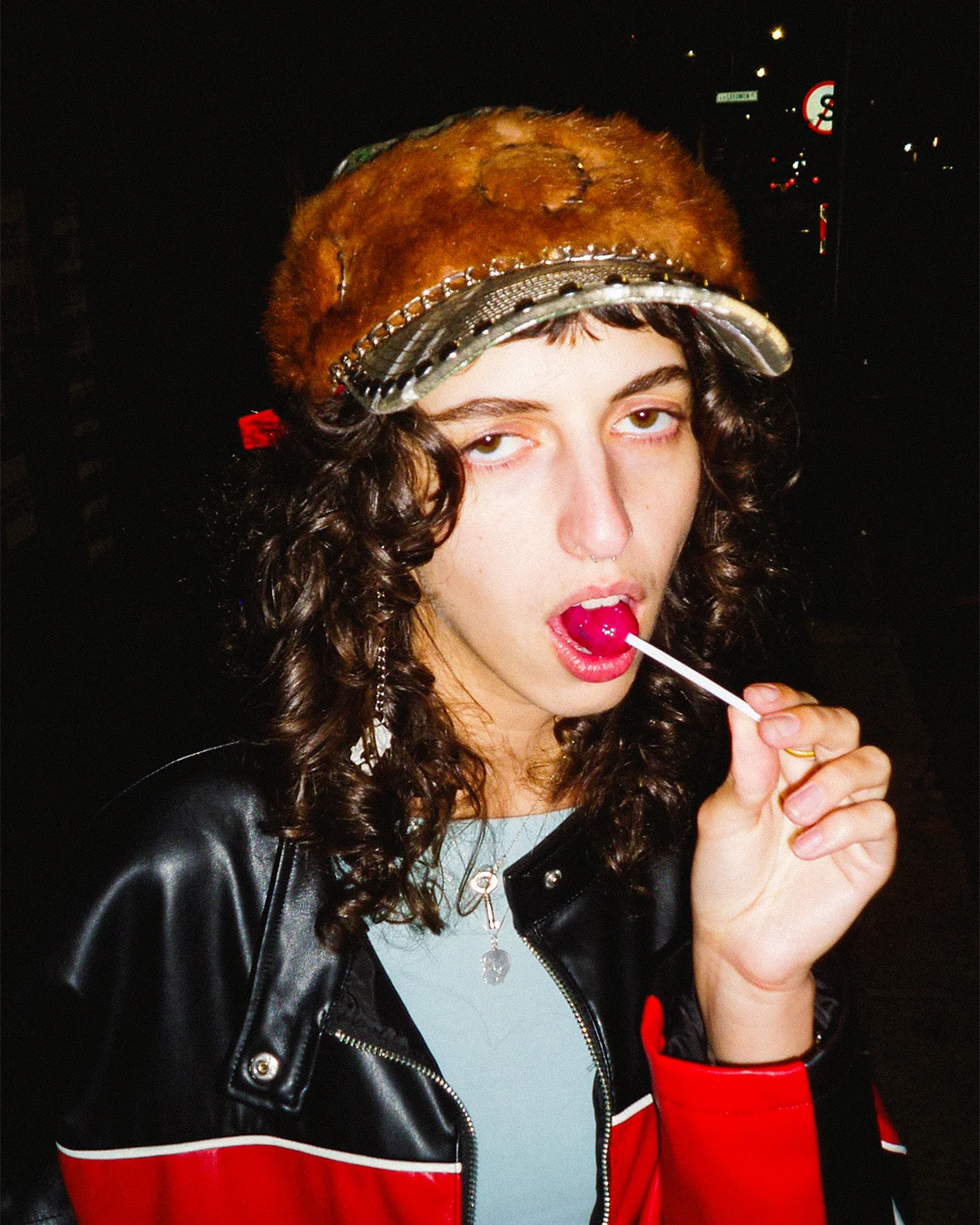 Person wearing a fur hat and leather jacket with a dark background