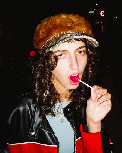 Person wearing a fur hat and leather jacket with a dark background