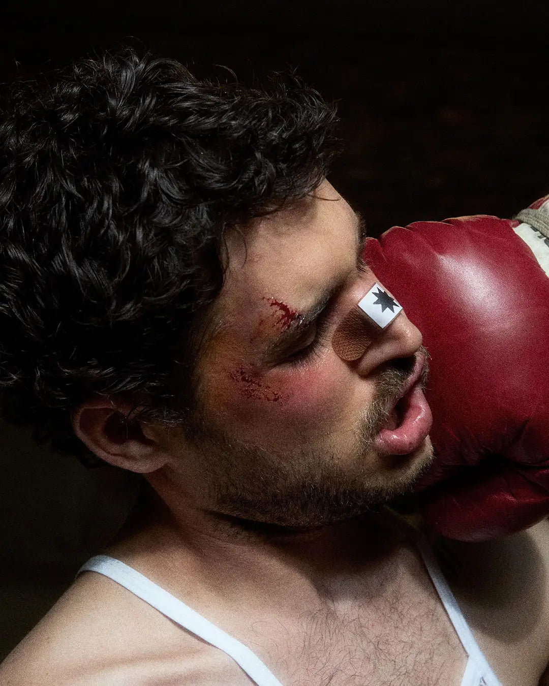 A man with a bloody nose, wearing a red boxing glove, embodies the fierce spirit of Bullyboy streetwear in Cape Town.