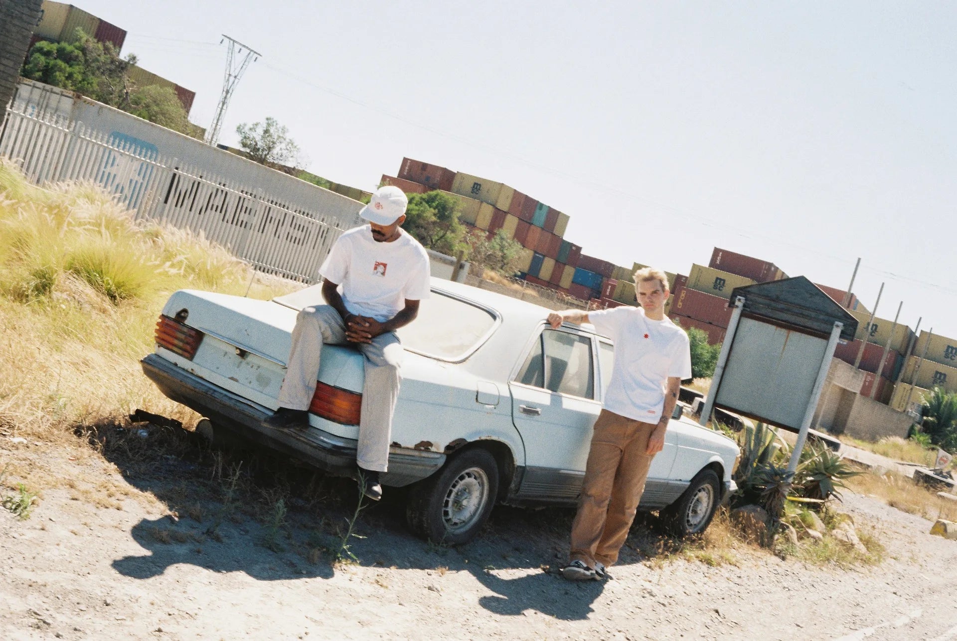 Two men dressed in Bullyboy streetwear relax on a car, showcasing South African fashion and a unique lifestyle