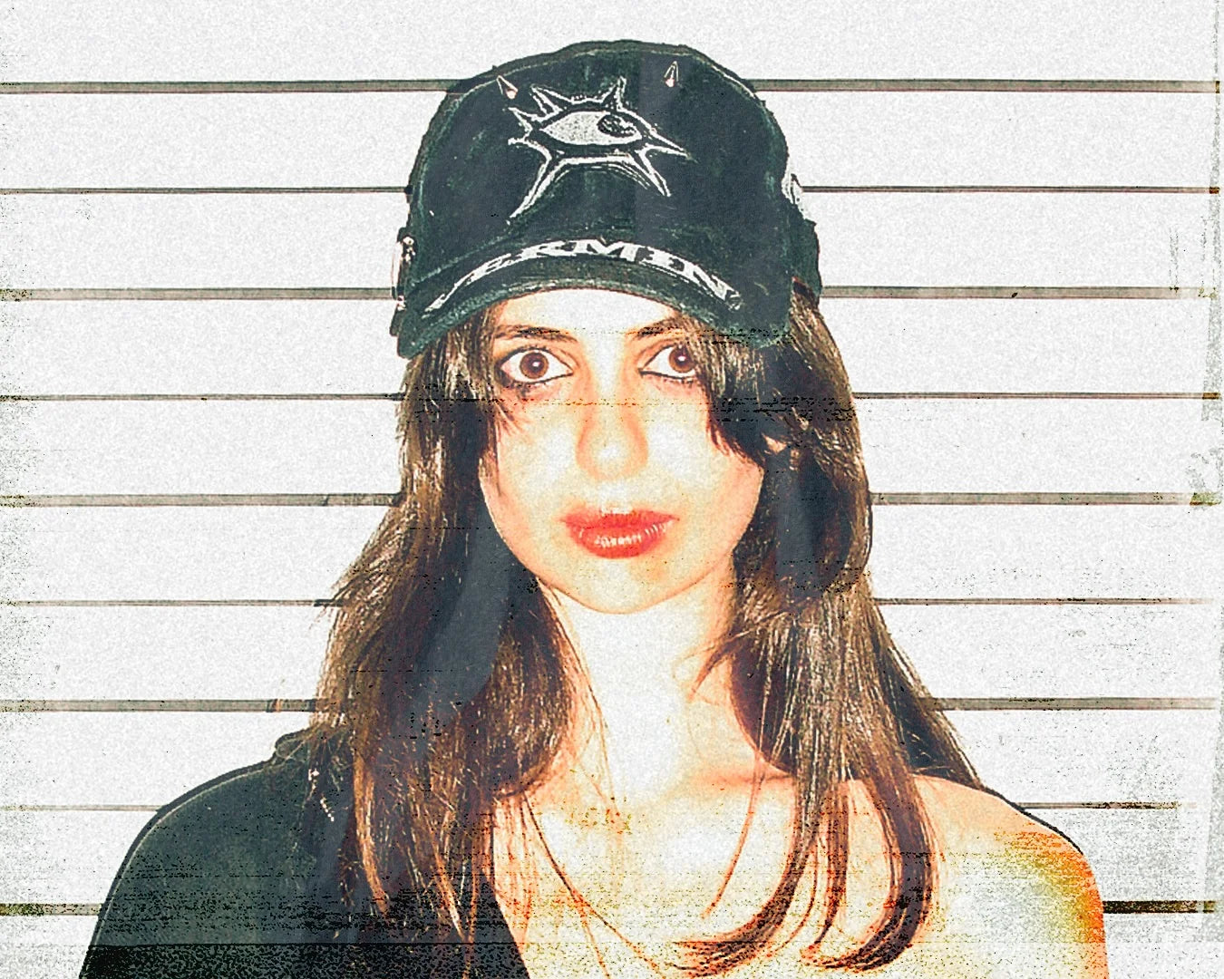 Person wearing a black cap with a logo against a wooden panel background