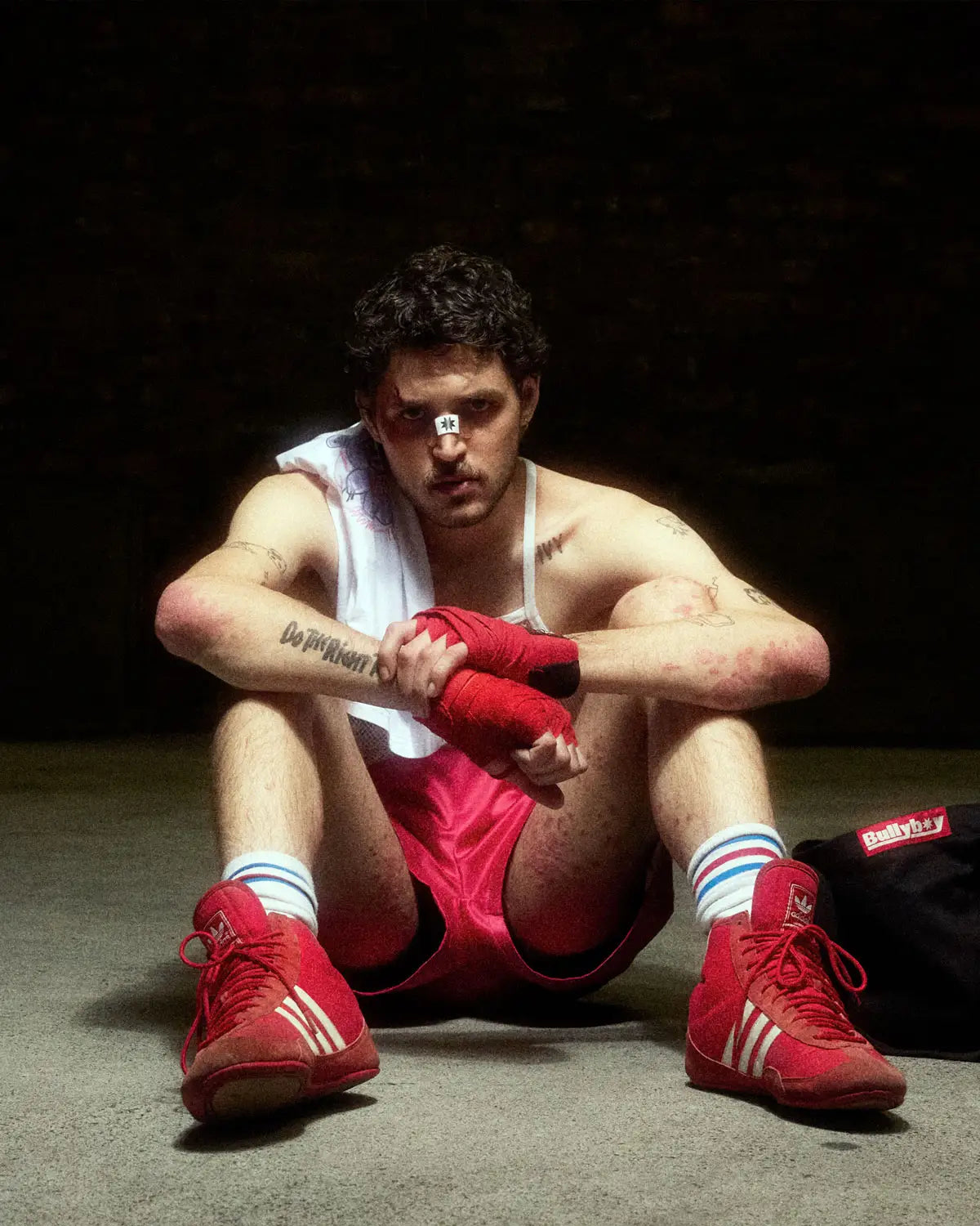 A man in boxing gloves sits on the ground, embodying the spirit of Bullyboy's premium streetwear in Cape Town.