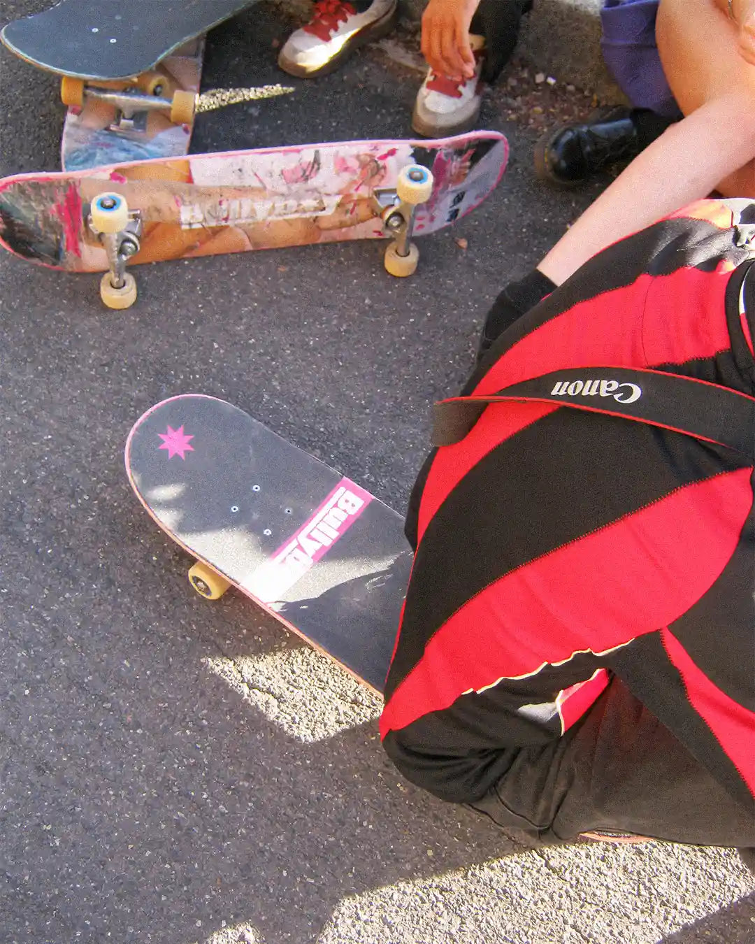 A person seated on the ground, embodying the spirit of the Skating Is Risky x Bullyboy skate edit collaboration.
