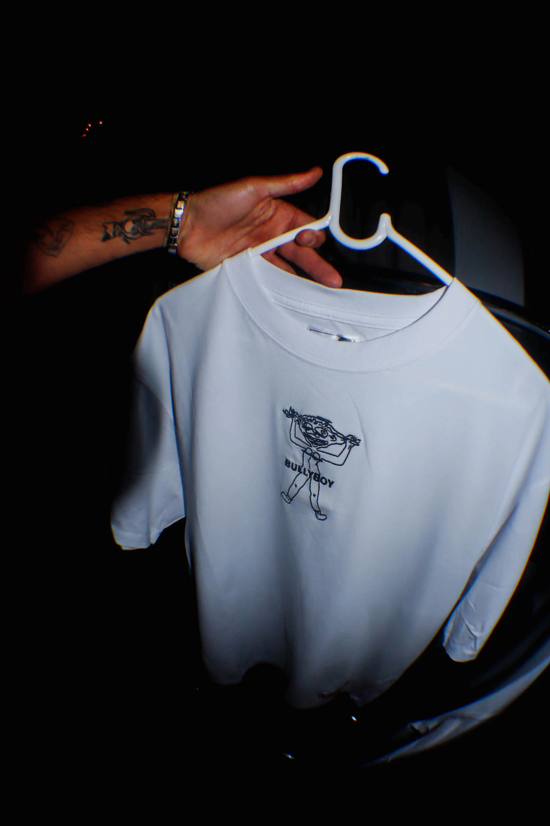 A stylish individual showcases a white t-shirt featuring a striking black and white design at the Buzzcut market in Cape Town